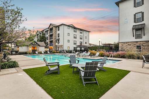 pool surrounded by lawn chairs at Vine + Vail Townhomes and Apartments, Texas