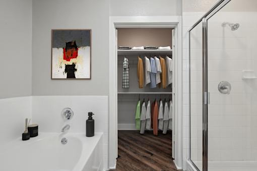 A bathroom with a white tub and a white door leading to a closet at Highline Urban Lofts Apartments, Cypress, Texas