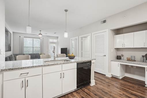 A modern kitchen with white cabinets and a wooden floor at Highline Urban Lofts Apartments, Cypress, Texas