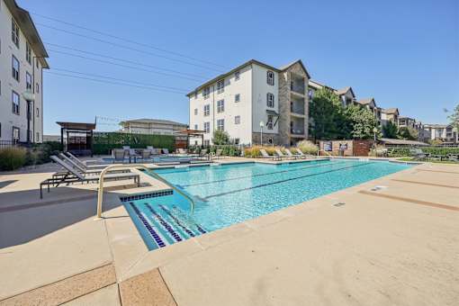 pool surrounded by a concrete floor at Vine + Vail Townhomes and Apartments, Grapevine, TX