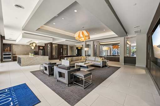 A spacious living room with a large grey sofa set and a grey rug at Everra Midtown Park Apartments, Dallas, Texas