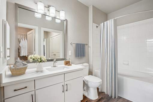 A white bathroom with a white toilet, sink, and bathtub at Highline Urban Lofts Apartments, Cypress, TX