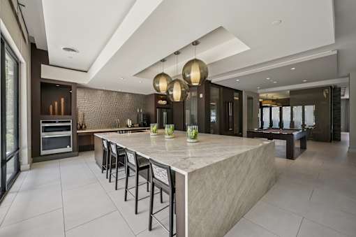 A modern kitchen with a large island and pendant lights at Everra Midtown Park Apartments, Dallas, TX, 75231