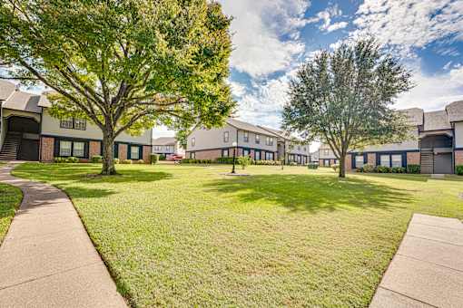 Courtyard with mature trees and walking paths at Arbors Of Cleburne Apartments, Cleburne, Texas