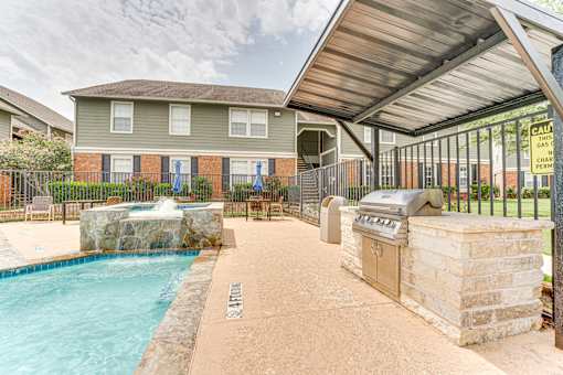 Outdoor pool area with waterfall and grill pavilion at Arbors Of Corsicana Apartments, Corsicana, TX 75110