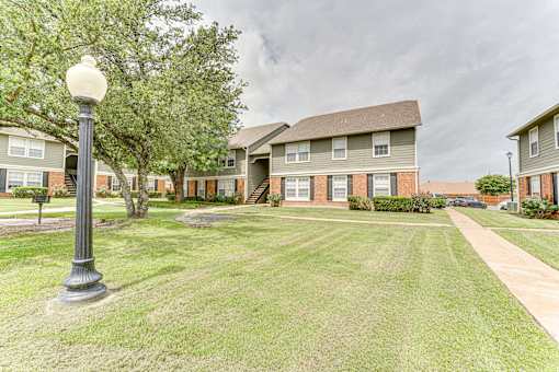 Two story apartment buildings with landscaped courtyard at Arbors Of Corsicana Apartments, Corsicana, Texas