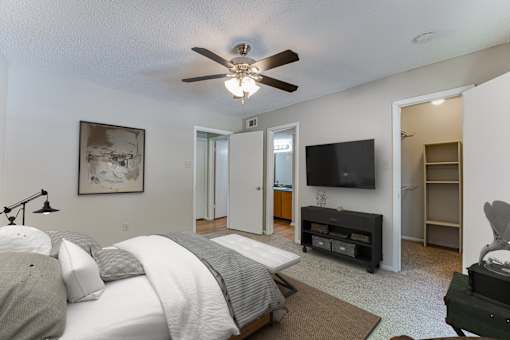 A bedroom with a large bed and a flat screen TV mounted on the wall.