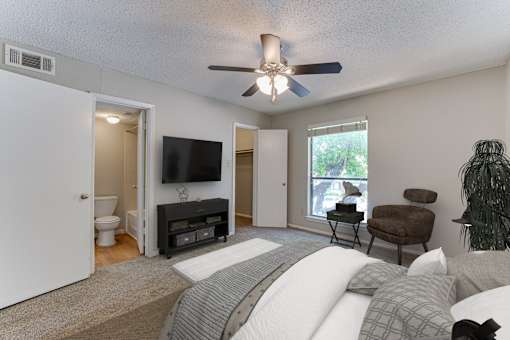 A bedroom with a bed, chair, and television.