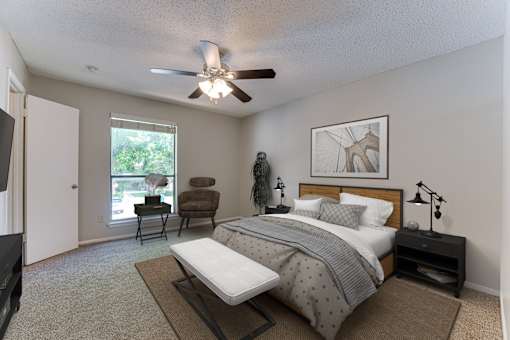 A bedroom with a bed, chair, and ceiling fan.