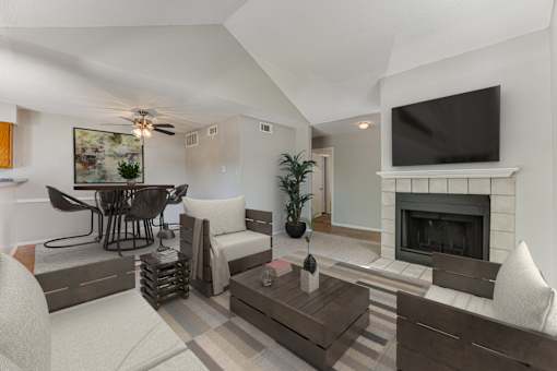 A living room with a fireplace and a television mounted above it.