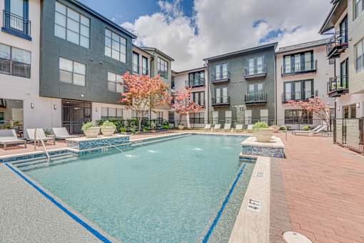 Outdoor swimming pool courtyard with lounge chairs at The Barton Apartments, Texas