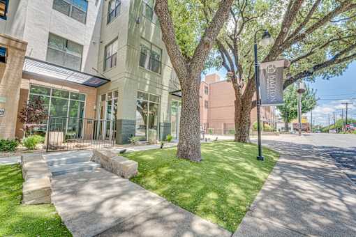 Building exterior with shaded courtyard lawn at The Barton Apartments, Dallas, TX