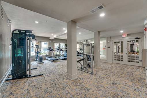 A gym with a variety of equipment including treadmills, weights, and exercise machines.