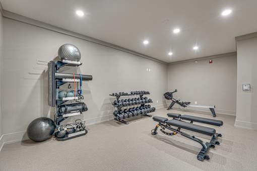 A room with a variety of exercise equipment including a weight rack, exercise balls, and resistance bands.