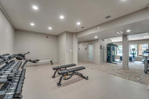 A spacious gym with treadmills, elliptical machines, and weight benches.