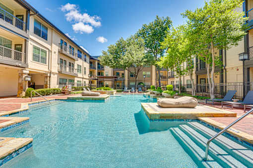 A swimming pool in a residential area surrounded by trees and buildings.