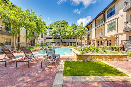 A pool surrounded by lawn chairs and trees.