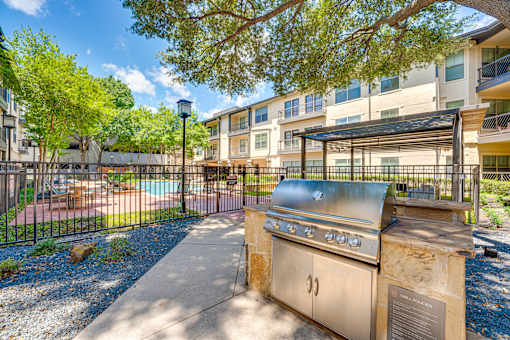 A BBQ grill is in front of a building with a pool.
