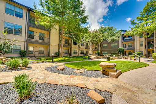 A sunny day at a residential complex with a well-maintained garden and a stone pathway.