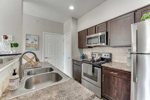 A kitchen with a stainless steel refrigerator, oven, and sink. at The Brazos, Dallas, 75287