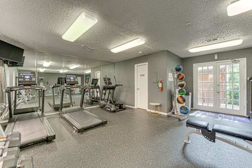 A gym with treadmills, exercise equipment, and a mirrored wall at Copper Hill Apartments, Texas, 76021