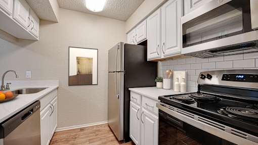A modern kitchen with black appliances and white cabinets at Copper Hill Apartments, Bedford, TX, 76021