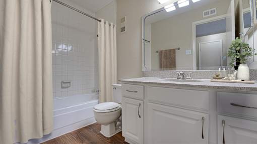 A white bathroom with a toilet, sink, and shower at Copper Hill Apartments, Texas
