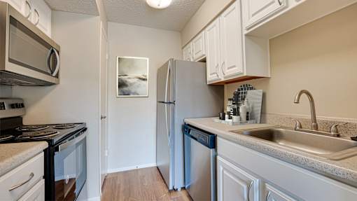 A kitchen with a refrigerator, stove, and dishwasher at Copper Hill Apartments, Bedford