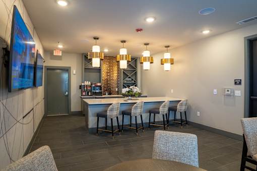 A modern bar area with a long counter and stools.