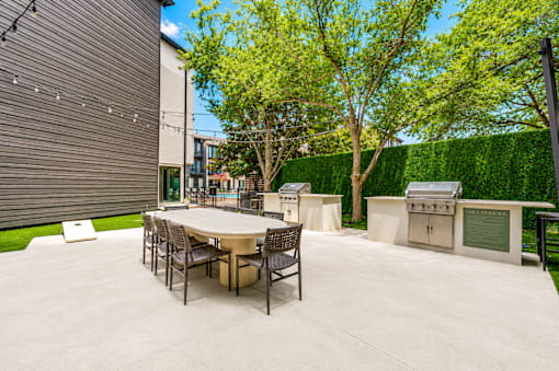Outdoor kitchen with grills and dining table at The Barton Apartments, Dallas, TX