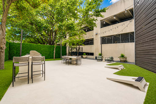 Outdoor entertaining patio with grilling station and string lights at The Barton Apartments, Dallas, Texas
