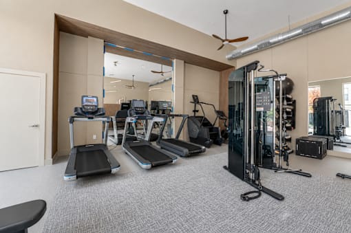 Fitness center with treadmills and cable machines at The Barton Apartments, Texas