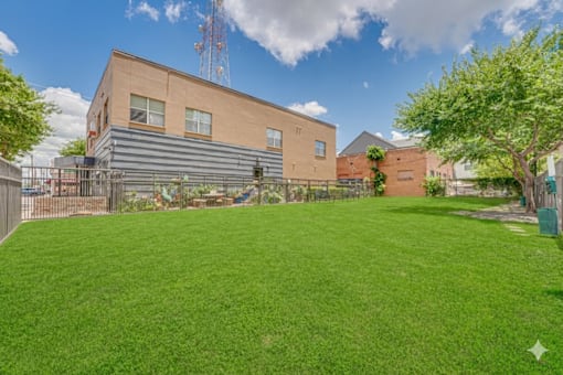 Spacious lawn area with community building at Vue Live Oak Apartments, Texas