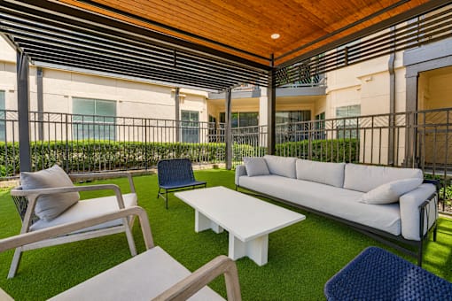 A patio with a white couch, chairs, and tables.