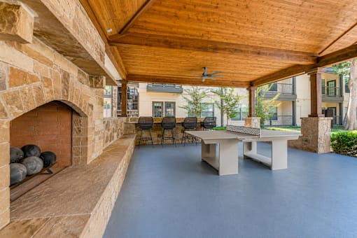 A room with a stone fireplace and a wooden ceiling.