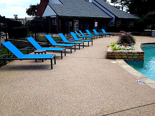 A poolside area with blue lounge chairs and a pool.