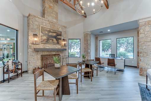 A modern dining room with a stone fireplace and wooden furniture at Limestone Ranch Apartments, Texas