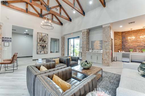A modern living room with a large grey sofa and a stone fireplace at Limestone Ranch Apartments, Lewisville, TX