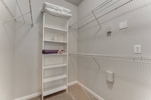 A white shelving unit with a purple yoga mat on the bottom shelf at Limestone Ranch Apartments, Lewisville
