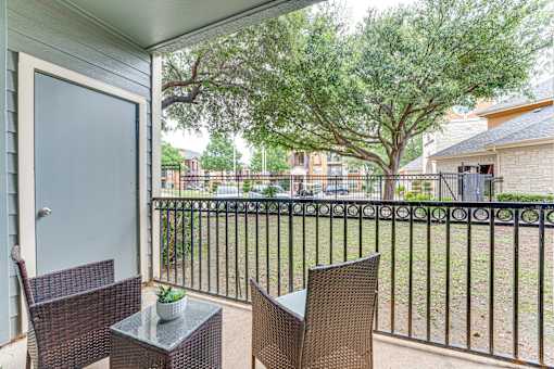 A patio with a table and chairs overlooking a fence at Limestone Ranch Apartments, Lewisville 75067