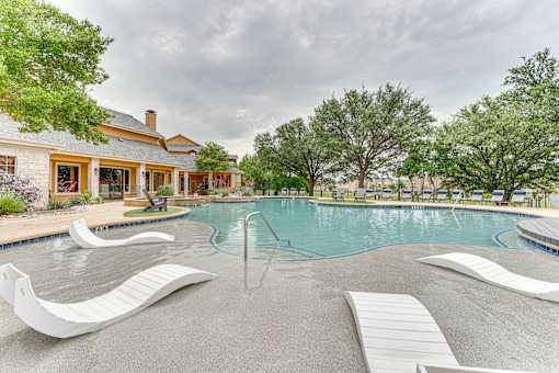A pool with a white slide and a house in the background at Limestone Ranch Apartments, Lewisville, TX