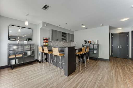 A modern kitchen with a wooden floor and a large island with chairs. at The Manhattan Apartments, Texas