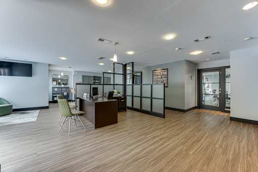 A modern office space with a wooden floor and a green chair. at The Manhattan Apartments, Dallas, Texas