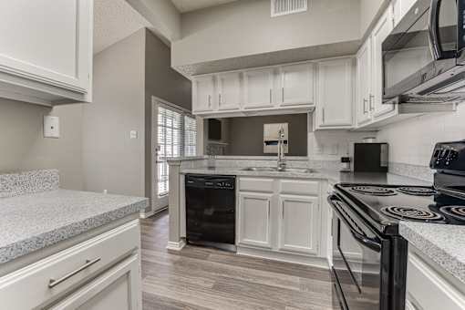 A kitchen with a black stove top oven. at The Manhattan Apartments, Dallas, TX, 75252