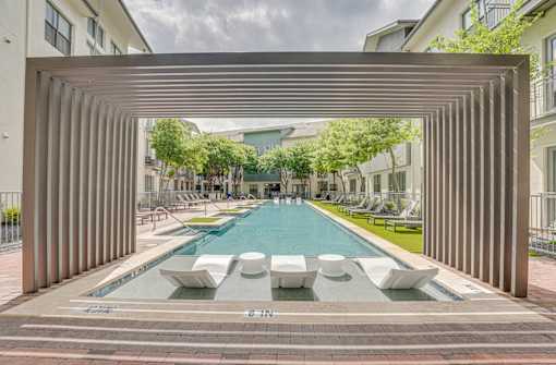 Pool with pergola and modern loungers at The Montrose Apartments, Dallas, TX