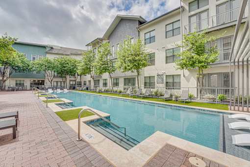 Courtyard pool with sunbathing areas and greenery at The Montrose Apartments, Dallas, Texas