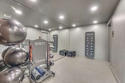 Fitness center with exercise equipment and mirrored walls at The Montrose Apartments, Dallas