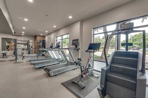 Fitness center with cardio equipment and large windows at The Montrose Apartments, Dallas, TX