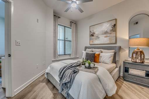 Bedroom with upholstered bed and arched mirror at The Montrose Apartments, Dallas, 75204