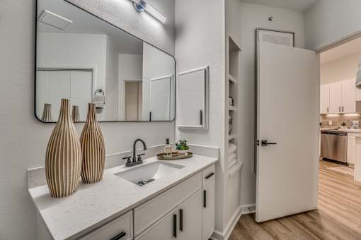 Bathroom vanity with white cabinetry and recessed shelving at The Montrose Apartments, Dallas